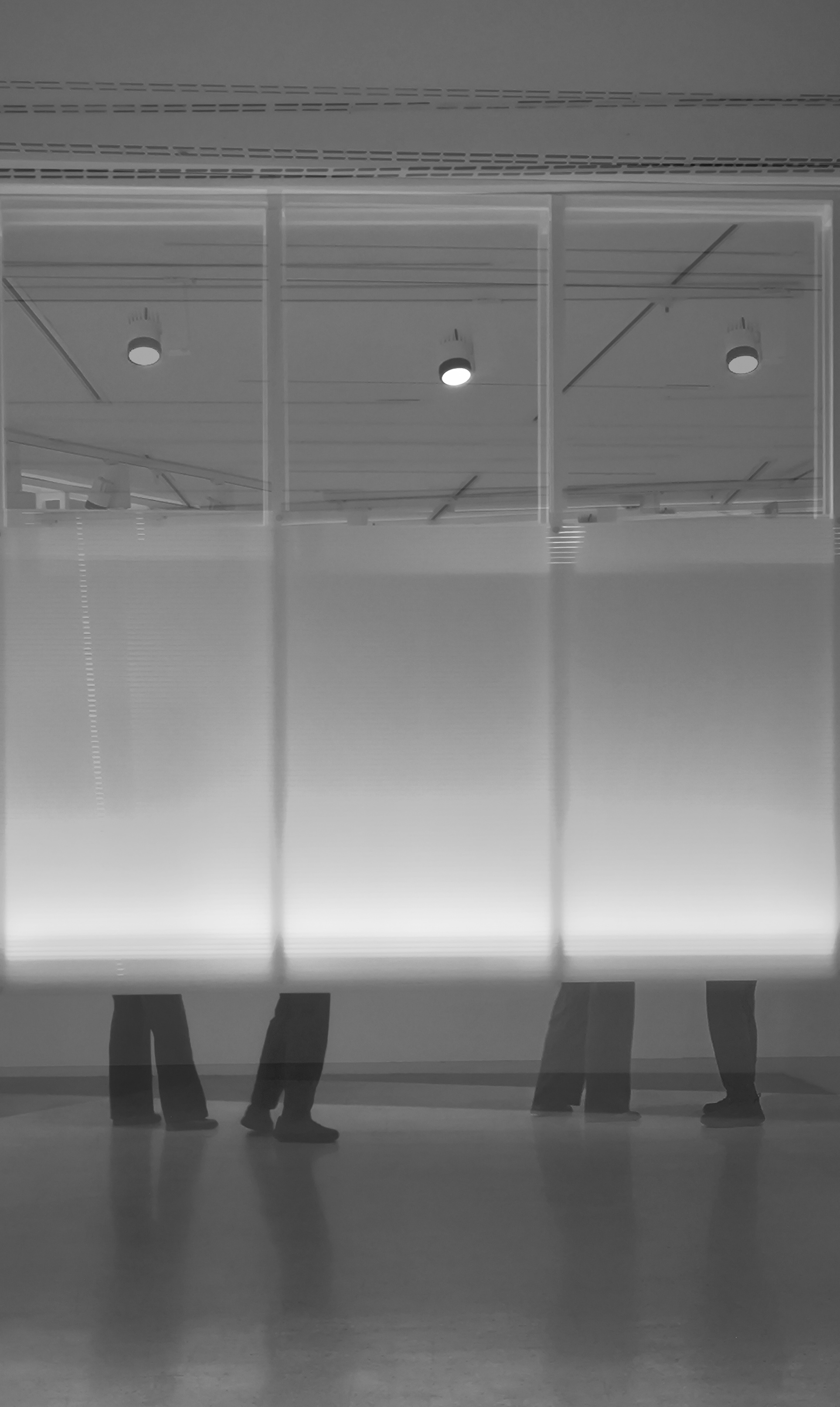 Dues imatges superposades que mostren les cames d'una parella que se segueixen i que es troben, darrere d'uns panells.