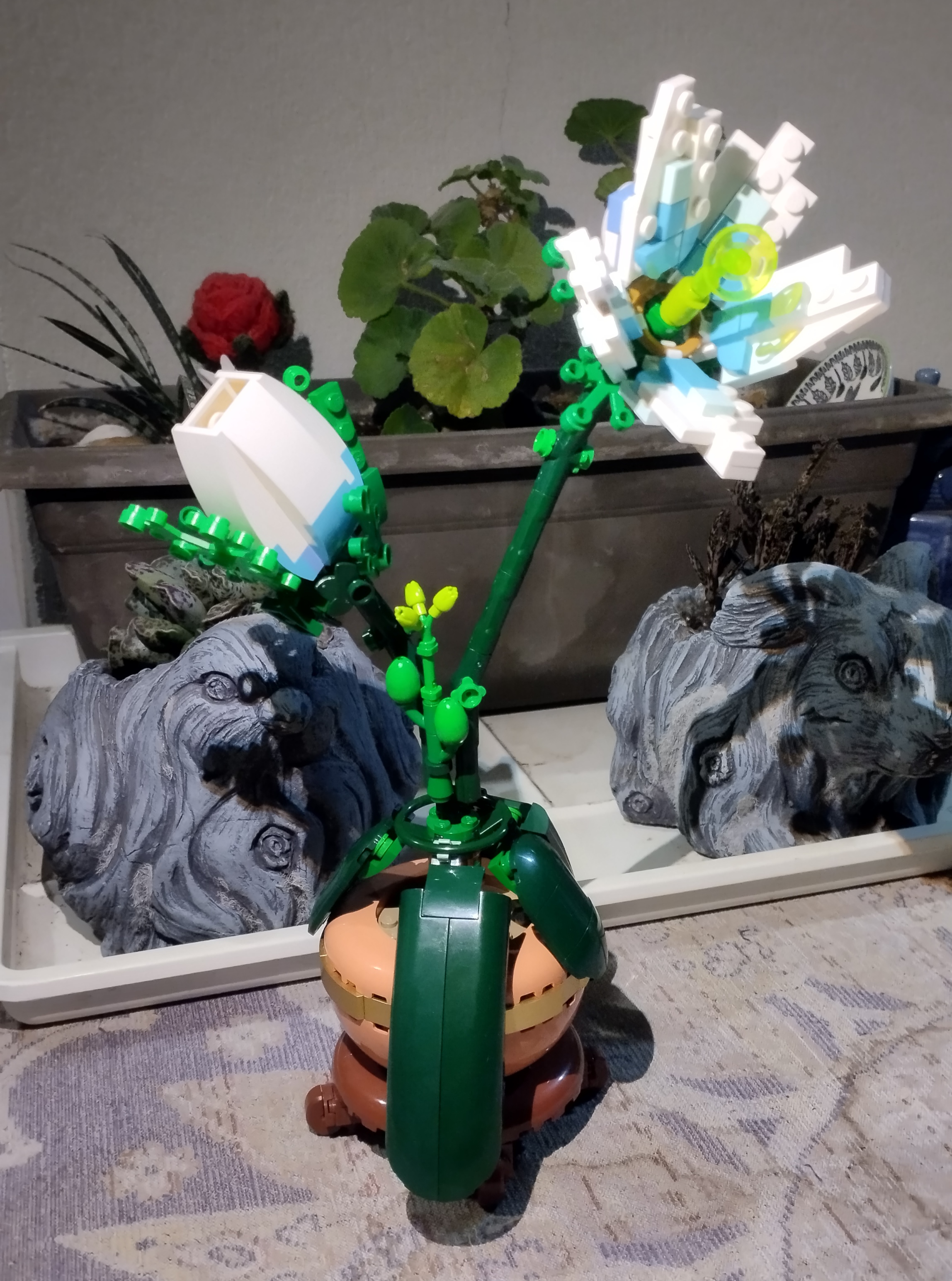 conjunto de  tiestos en una mesa. en medio se ve una planta de Lego que imita la princesa de la calma de zelda breath of the world y tears of the kingdom.