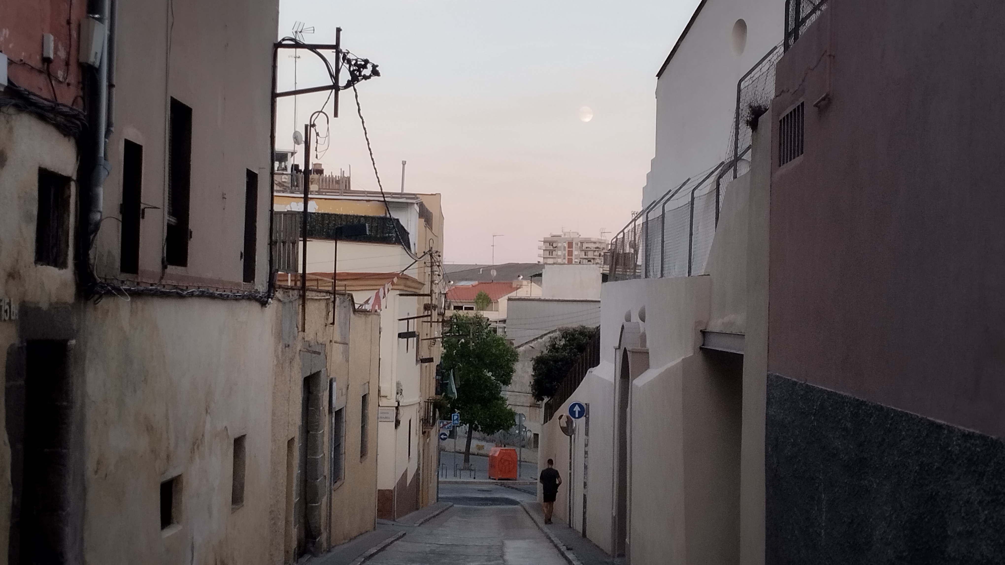 vista de una calle en bajada. se ve que llega a una plaza con árboles